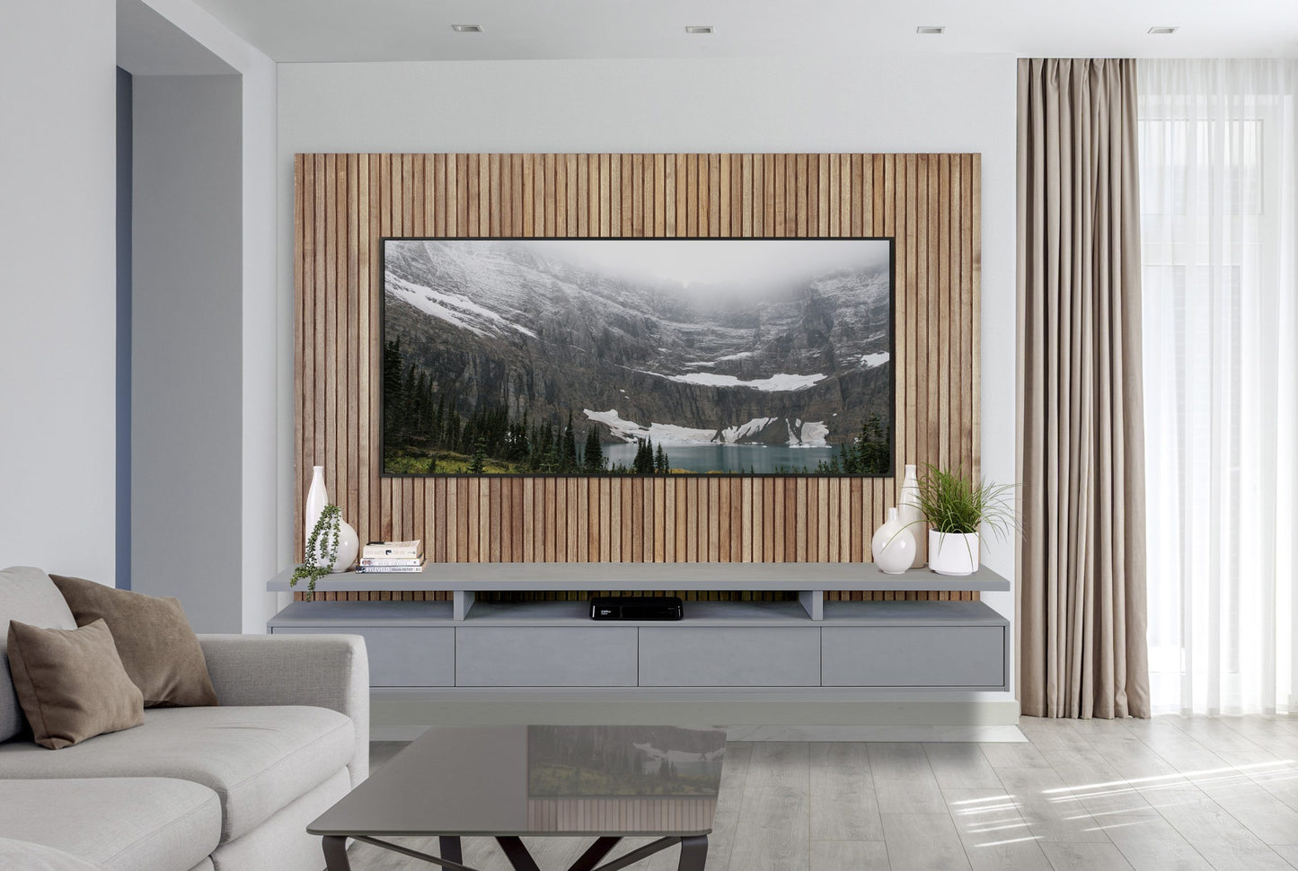 A sleek, modern living room featuring a large flat-screen tv mounted on an oak slatted wood backboard, with a minimalist gray console below, flanked by decorative plants.