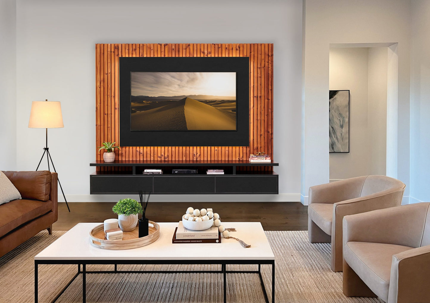 A modern living room with a large framed television on a wall-mounted tv stand, flanked by stylish shelves and cozy, neutral-toned furniture illuminated by warm ambient lighting.