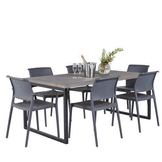 A modern dining setup featuring a sleek wooden table with six charcoal grey dining room chairs set of 6, completed with a bottle of champagne on ice, two glasses, and a vase with fresh greenery