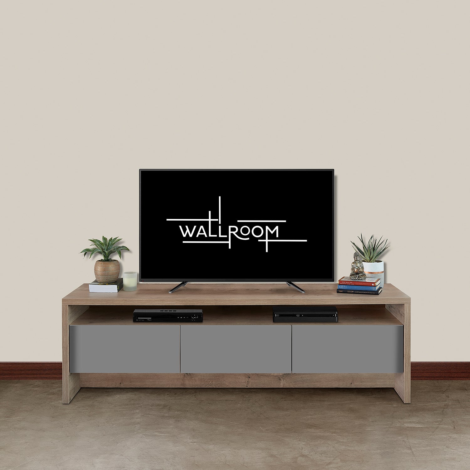 A minimalist living room with a flat-screen tv on a wooden media unit with 3 x grey pull open drawers for storage , flanked by two small potted plants and accompanied by a soundbar and a few decorative items.