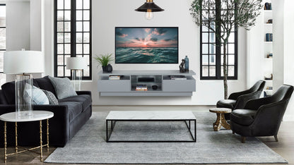 A modern living room featuring a large wall-mounted tv with an adjacent stylish wall mounted tv shelf, a dark sofa, armchairs, a marble coffee table, and stylish shelves against a neutral color palette